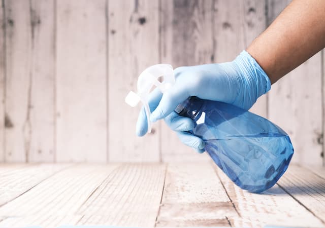 Blue spray bottle held with blue gloved hang